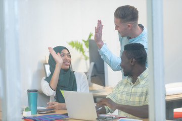 Business people giving high five while working together at desk in a modern office