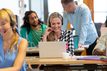 Female customer service executive talking on headset and working on computer in a modern office