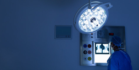 Male surgeon reading x ray in operating room at hospital