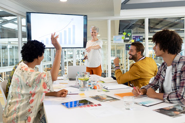 Businessman raising hand in presentation during meeting in a modern office