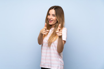 Young woman over isolated blue background pointing to the front and smiling