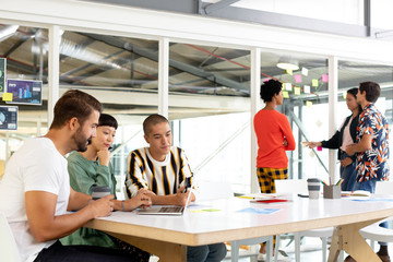 Business people discussing over laptop and sticky notes in the conference room