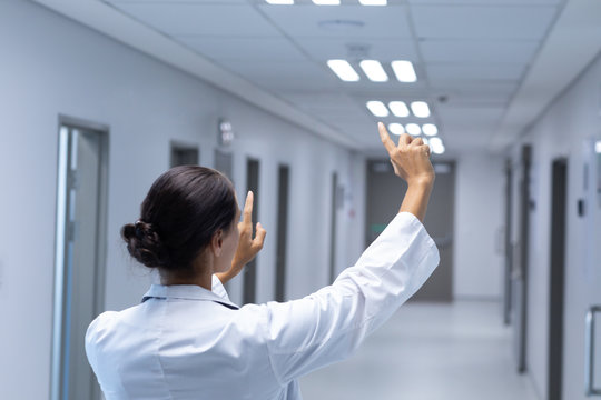 Female doctor pretending to touch an invisible screen in the corridor at hospital