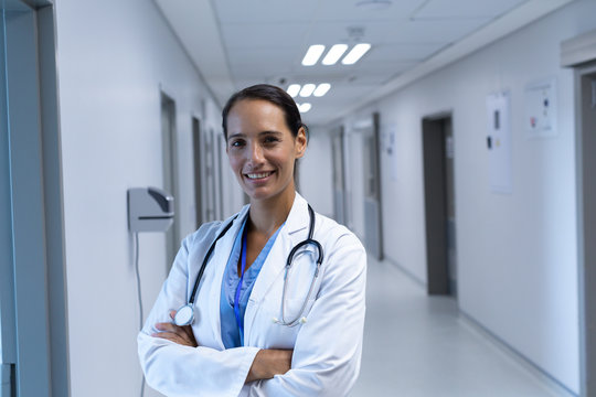 Female doctor with arms crossed looking at camera in the corridor at hospital