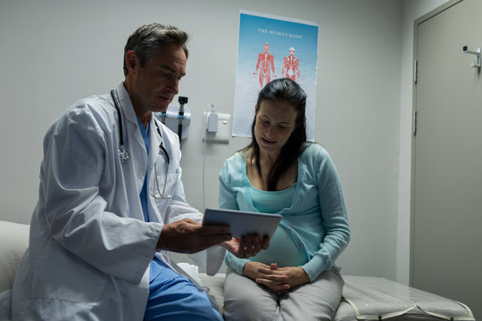 Doctor discussing medical report on digital tablet with pregnant woman