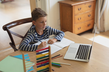 Boy doing homework at table in a comfortable home