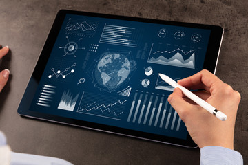 Business woman verifying reports on tablet with pencil in business suit
