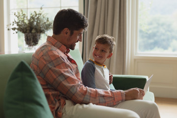 Father and son using laptop in living room