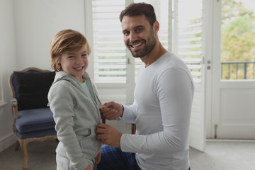 Fototapeta premium Father helping son putting on clothes 