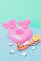 Girl in bikini with white flowers and yellow hat sunbathing near swimming pool and inflatable rubber ring. Tropical party. Flat lay, aerial view