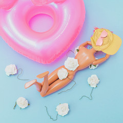 Girl in bikini with white flowers and yellow hat sunbathing near swimming pool and inflatable pink rubber ring. Tropical beach party. Flat lay, aerial view