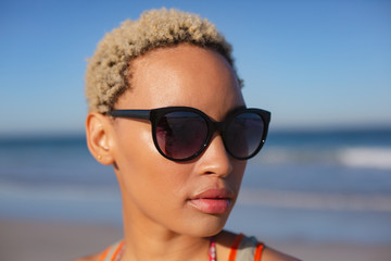 Beautiful woman in sunglasses looking away on beach in the sunshine