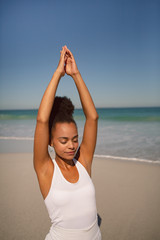 Fototapeta na wymiar Beautiful woman doing yoga at beach in the sunshine