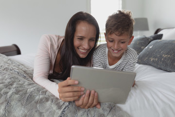 Fototapeta premium Mother and son using digital tablet in bedroom at home