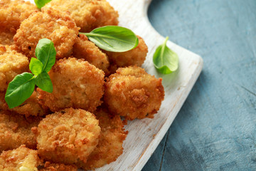 Fried Mac, macaroni and Cheese Bites in breadcrumbs with ketchup sauce on white wooden board