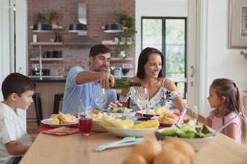 Family having food and champagne on dining table at home