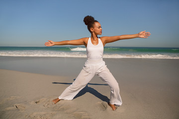 Beautiful woman doing yoga at beach in the sunshine