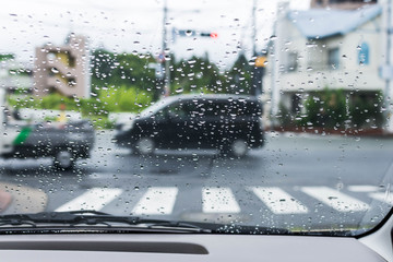 Rainy and gloomy day on the road with cars and traffic and rain is focused on the car's windshield. 