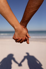 Couple holding hands on beach in the sunshine