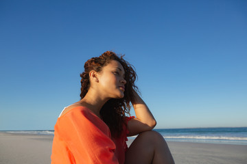 Beautiful woman sitting and looking away on beach in the sunshine