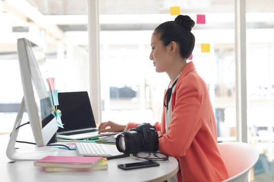 Female graphic designer working on laptop at desk in a modern office