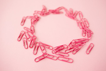 Scattered pink paper clips. Pink background. Flatlay. Copy space