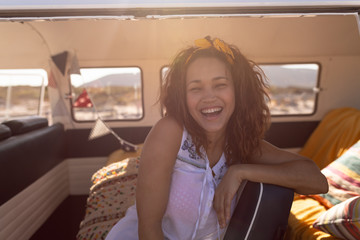 Happy young woman sitting in camper van at beach