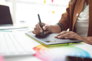 Female graphic designer using graphic tablet at desk in a modern office