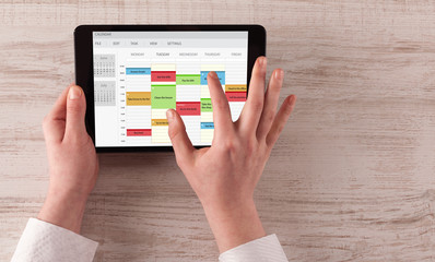 Fototapeta na wymiar Hand holding tablet with timetable and calendar concept
