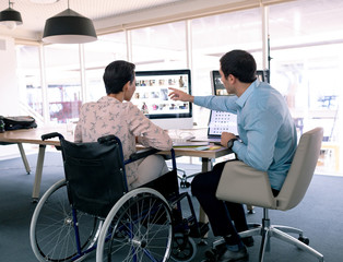 Graphic designers discussing over computer at desk in a modern office