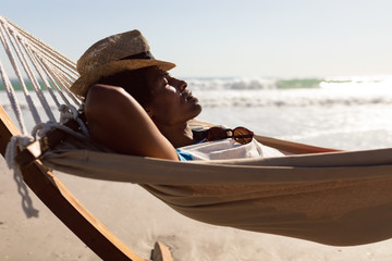 Man with hat sleeping in a hammock on the beach - Powered by Adobe