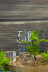 Ice cubes and mint leaves isolated on wooden cutting board