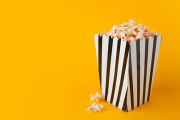 Popcorn in paper bag stand on yellow background side view