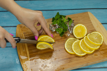 Woman slicing lemon on a wooden cutting board in the kitchen