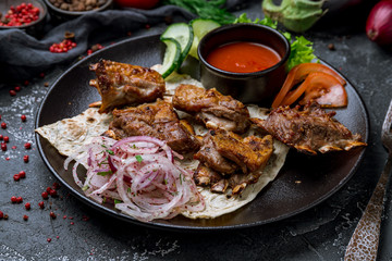 Kebab from lamb ribs on black plate