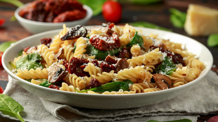 Fusilli Pasta with sun dried tomatoes, mushrooms, parmesan cheese and spinach. healthy food.