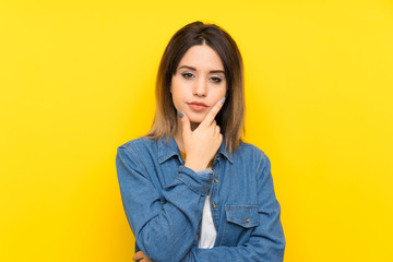 Young woman over yellow background thinking an idea