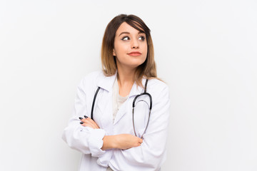 Young doctor woman over isolated background making doubts gesture while lifting the shoulders