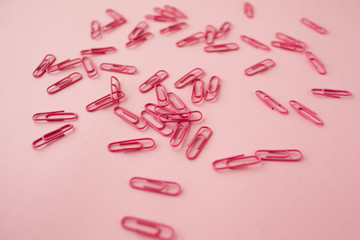 Scattered pink paper clips. Pink background. Flatlay.