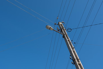Street lamppost with wires. Concrete pole with a lantern. Street lamp with a bird.