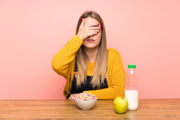 Young woman with bowl of cereals covering eyes by hands
