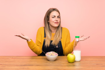 Young woman with bowl of cereals having doubts with confuse face expression