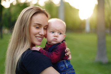 Beautiful young mother walks with her little son in a summer park