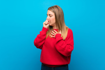 Woman with red sweater over blue wall is suffering with cough and feeling bad