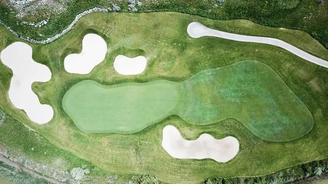 Aerial Shot of a par 3 hole on a golf course. You can see four sand traps and the cart path as well.