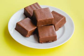 Chocolate sweets on a plate on a yellow background.