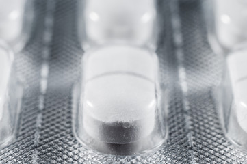 White pills with two lobes in special medical sticks, close-up