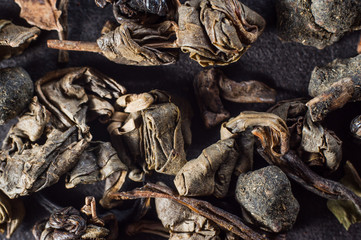 large leaves of dried green tea in a compressed state on a dark background