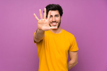 Handsome over isolated purple wall counting five with fingers