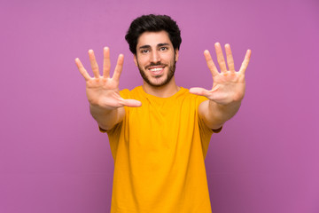 Handsome over isolated purple wall counting ten with fingers